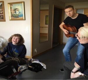 Arvid Pereswetoff-Morath (giarr), Marcus Wiander (percussion) och Betty Fjällström (sång) musicerar för en kvinna på ett äldreboende i Sundbyberg. Foto: Ulrika Kron